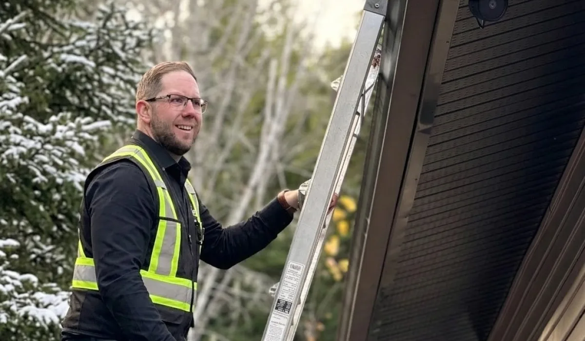 Professional home inspector performing a winter roofline check on site