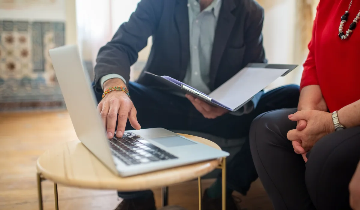 Two people reviewing permits and repair documentation on a laptop